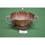 Art Nouveau beaten copper bowl with three white metal scrolled handles, standing on a circular base,