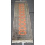 Rust ground carpet runner having yellow and black pattern with end tassels, signed in corner - 3m