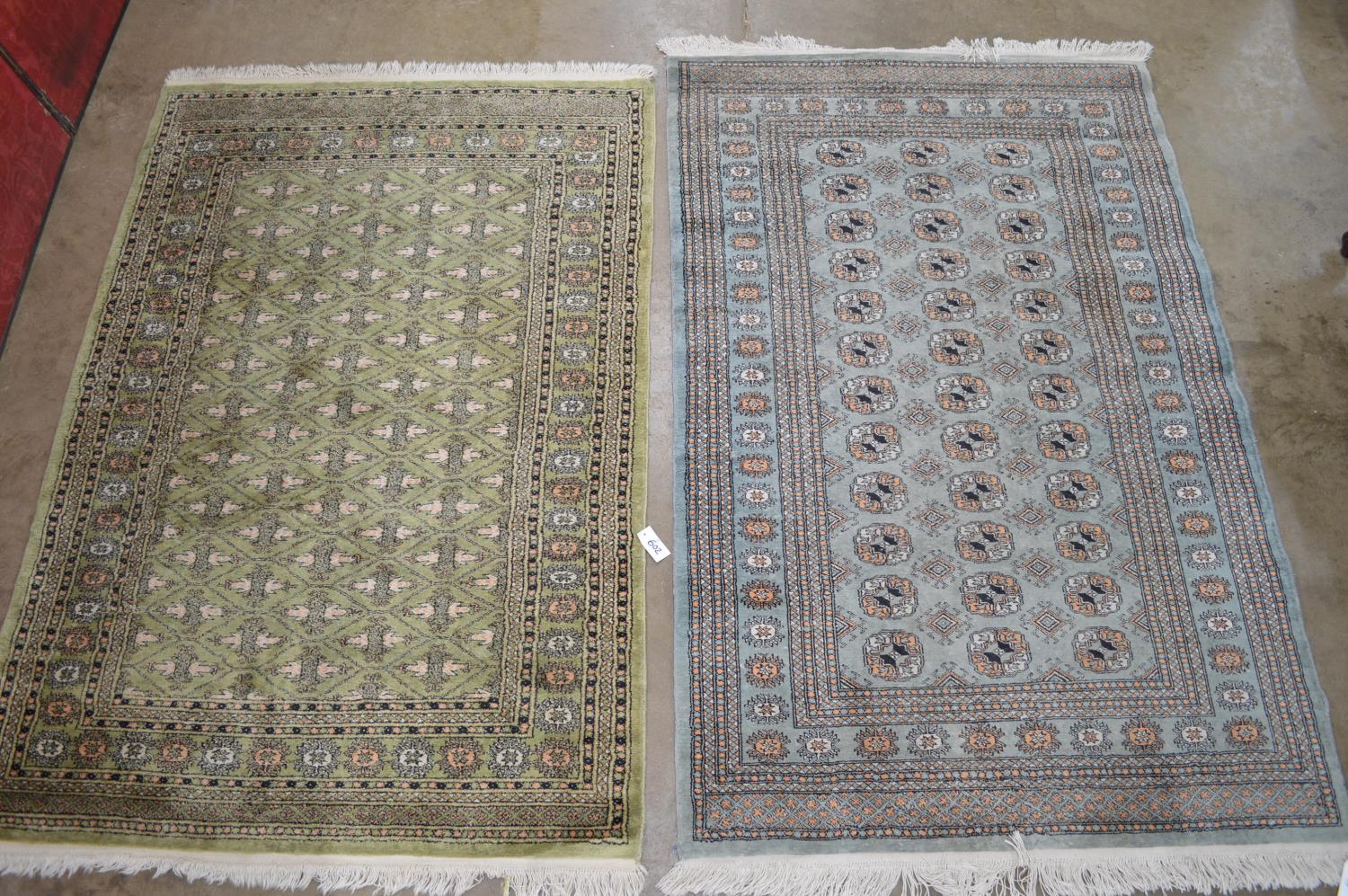 Two green ground rugs with end tassels - 75" x 49" and 80" x 48" Please note descriptions are not