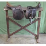 Pine saddle rack and two brown leather saddles Please note descriptions are not condition reports,