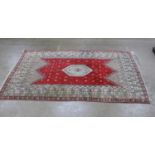 Patterned rug on a red and cream ground with tassels - 3.10m x 1.97m Please note descriptions are