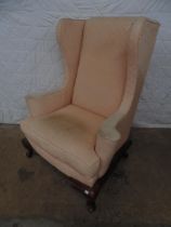 Wing back armchair having scrolled arms and standing on cabriole legs Please note descriptions are