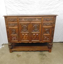 Highly carved oak sideboard with two central doors opening to reveal single shelf and flanked by two