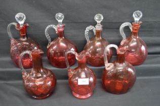 Group of seven Victorian Cranberry glass decanters with clear glass handles (three missing stoppers)