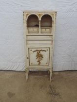 Cream and gilt cabinet having three drawers and arched recess over cupboard base, standing on