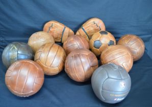 Group of ten leather footballs together with a pair of leather boxing mitts Please note descriptions