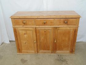 Victorian pine dresser base having three drawers over three doors opening to reveal single shelf,