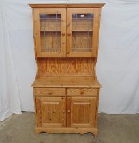 Modern pine dresser with two glazed doors opening to single shelf over two drawers and two solid