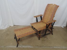 Rattan steamer chair having wooden frame with reclining back and footstool, the Rattan having a