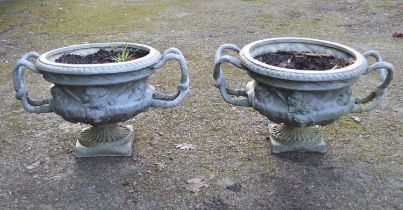 Pair of 20th century lead garden urns the bowls decorated with faces and having root formed handles,