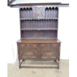 Oak dresser with shelved upper section and two short drawers over two cupboard doors to base,