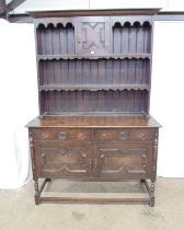 Oak dresser with shelved upper section and two short drawers over two cupboard doors to base,