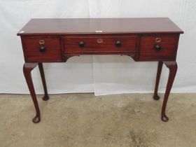 Mahogany side table having three drawers with knob handles, standing on cabriole legs ending in