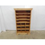 Pine music cabinet comprising three shelves over nine pigeon holes, standing on shaped plinth base -