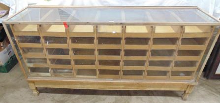 Light oak haberdashery display counter with thirty four drawers (one missing) having cup handles,