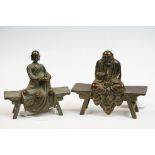 Two bronze ornaments of Buddha seated on benches.