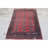 Persian Red Ground Bokhara type Wool Rug decorated with twenty seven guls within a border, 125cm x