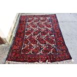 Persian Red Ground Wool Rug with geometric stylised pattern, 160cm x 208cm