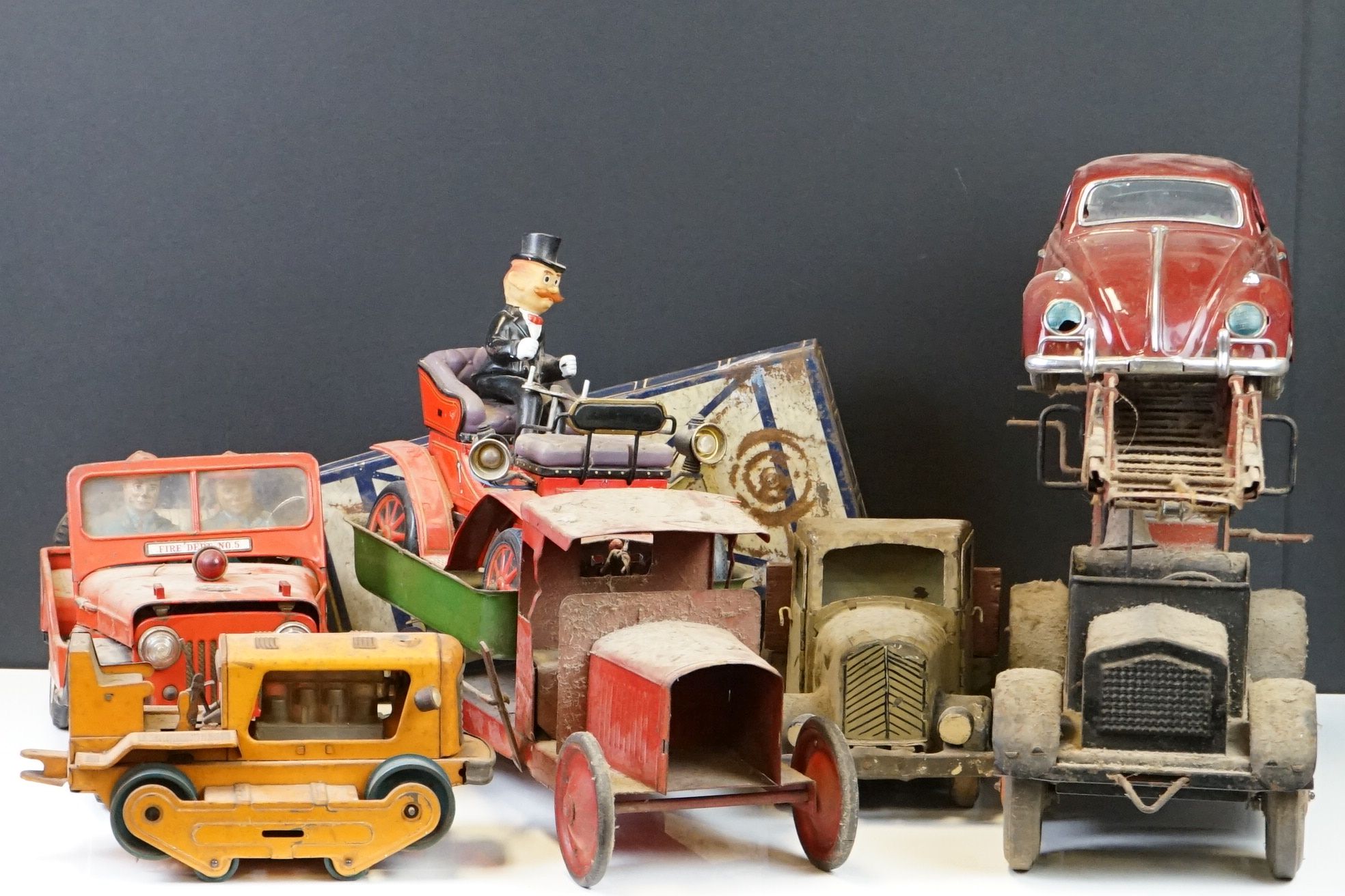 Six mid 20th C play worn tin plate models to include VW in maroon, fire engine with extending