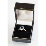 Sapphire and diamond 18ct yellow and white gold set cluster ring, the oval mixed cut sapphire