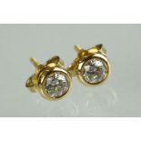 Pair of diamond solitaire 14ct yellow gold stud earrings, the round brilliant cut diamonds each