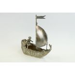 Late 19th Century continental silver model of a boy sat on a small sailing boat, the boat with