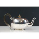 George V silver bachelors teapot of squat plain polished form with scrolling ebonised handle and