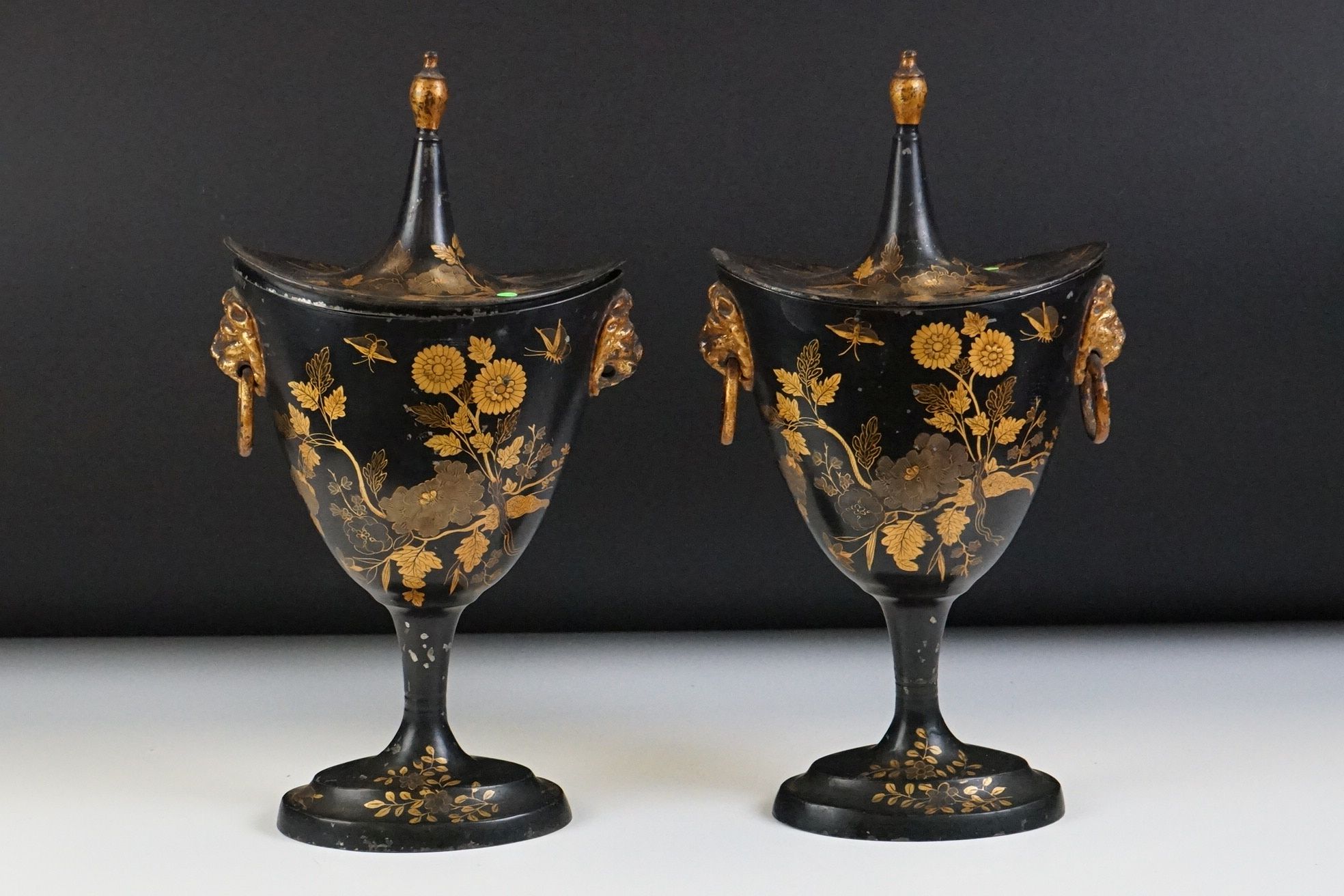 Pair of 20th Century Japanned helmet-shaped metal urns & covers with twin lion mask loop handles (