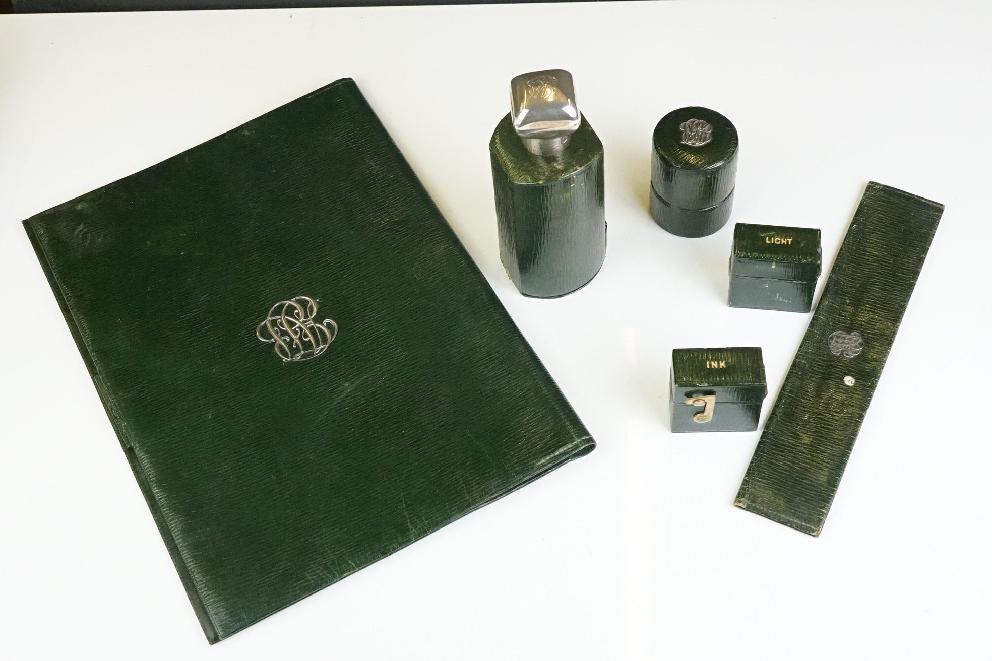 A collection of green leather travel accessories to include vesta case, ink well, folder and