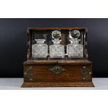 Late 19th Century Brass Mounted Oak Three Bottle Tantalus, housing three cut glass decanters (2 with