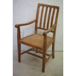 Early 20th century Arts and Crafts style Pale Oak Elbow Chair with slatted back and rush seat,