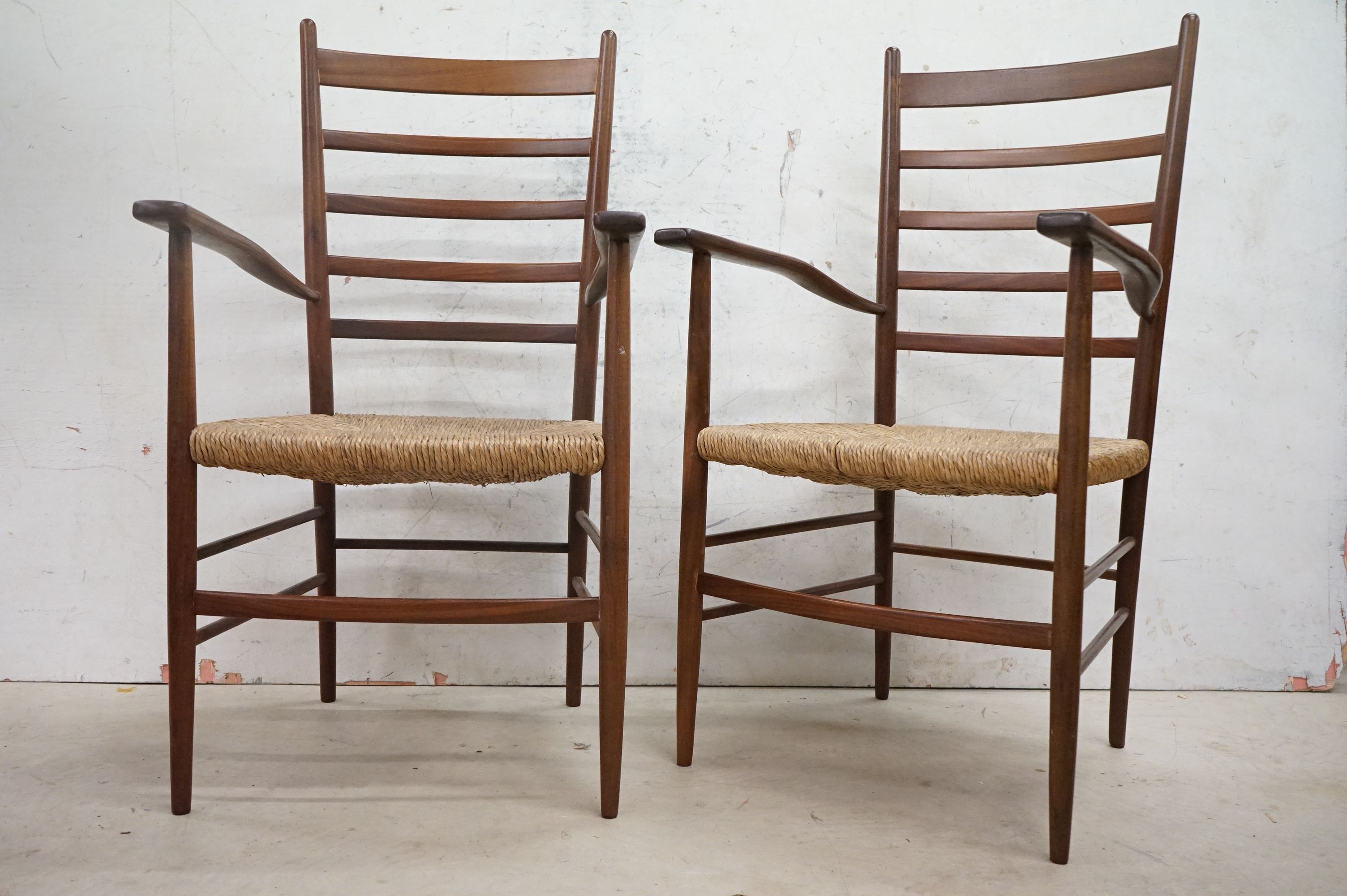 In the manner of Scadart, Pair of Mid century Retro Teak Ladder Back Elbow Chairs with rush seats,