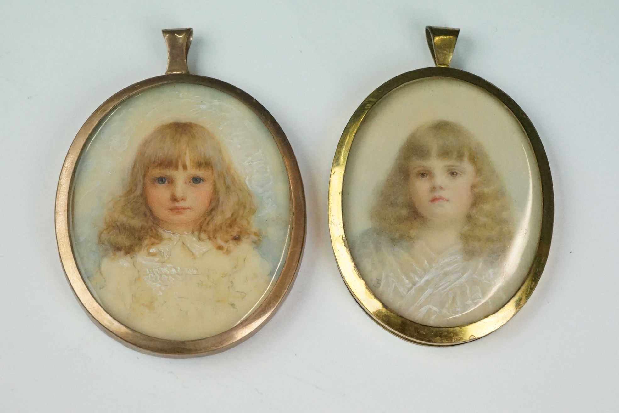 Two hand painted miniature portraits in yellow metal frames.