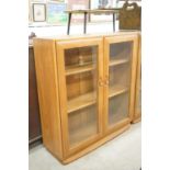 Ercol Pale Elm Bookcase / Display Cabinet with two bevelled glazed doors enclosing adjustable