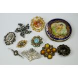 A collection of vintage brooches to include a silver example together with a powder compact.