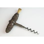 An antique corkscrew bottle opener with turned wooden handle and brush end.