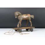 An antique wooden pull along horse toy with moving head and tail