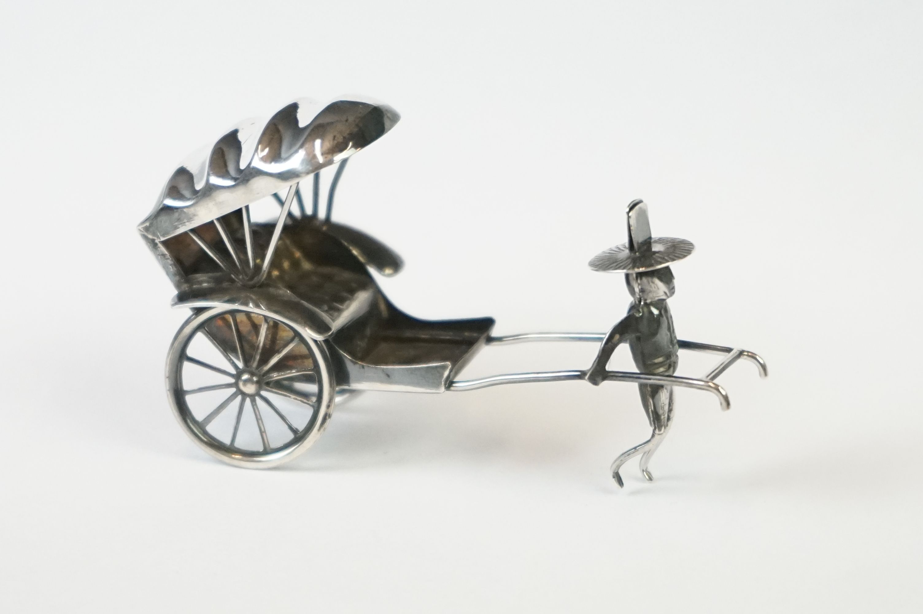 A Chinese sterling silver ornament of a man pulling a rickshaw.