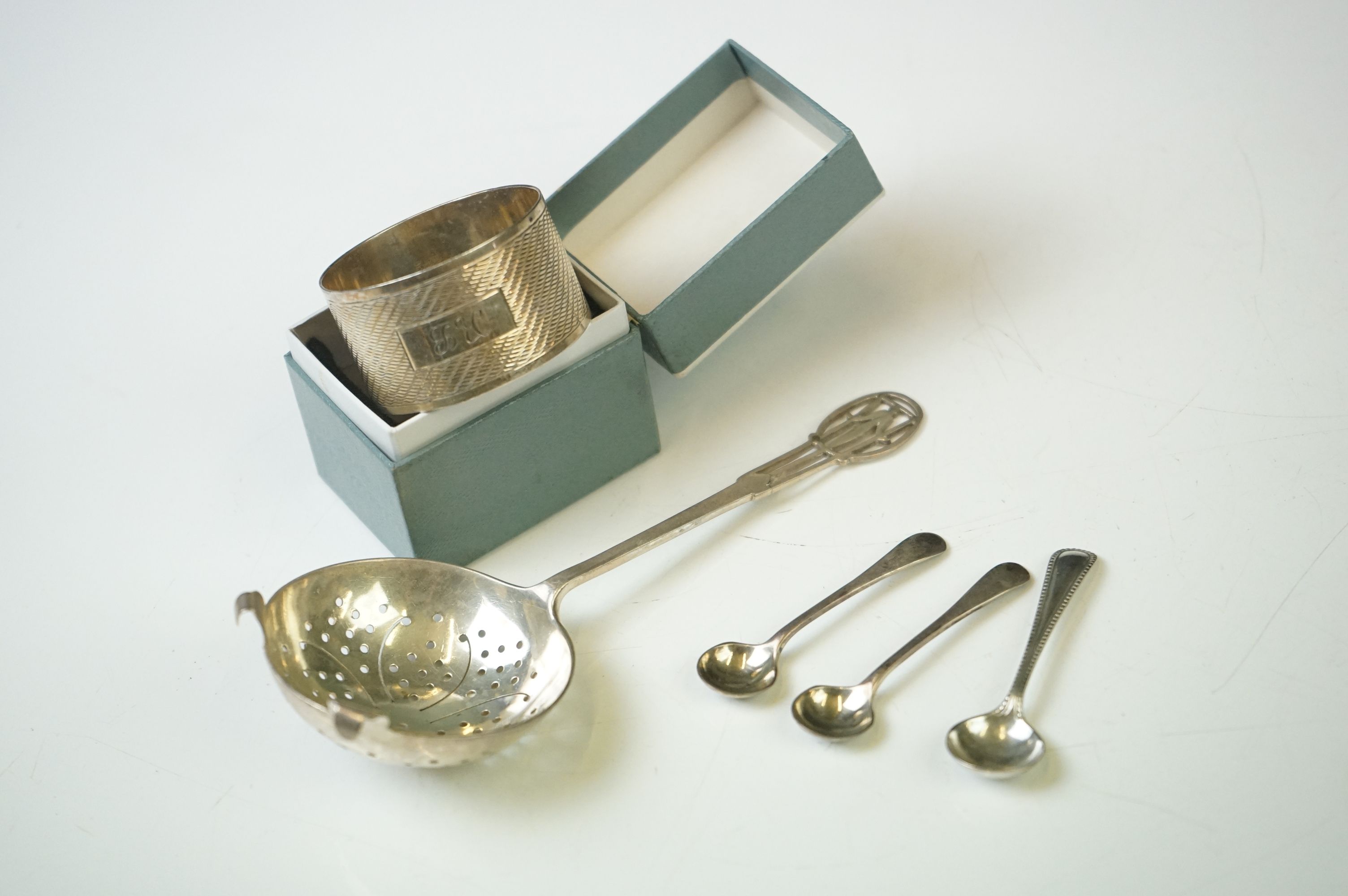 A small collection of hallmarked sterling silver to include a tea strainer, napkin ring and three
