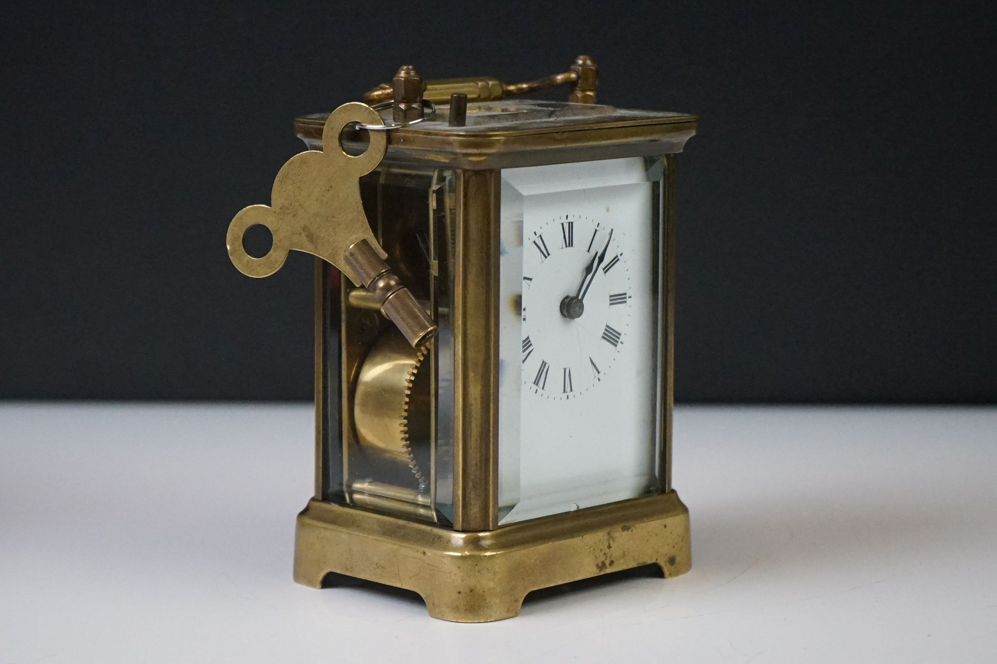 A brass cased carriage clock with beveled glass panels and white enamel dial, complete with key. - Image 2 of 15