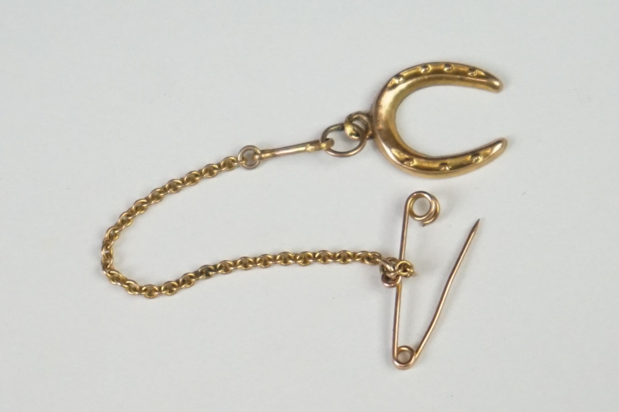 A small yellow metal lucky horse shoe with safety chain attachment. - Image 2 of 6