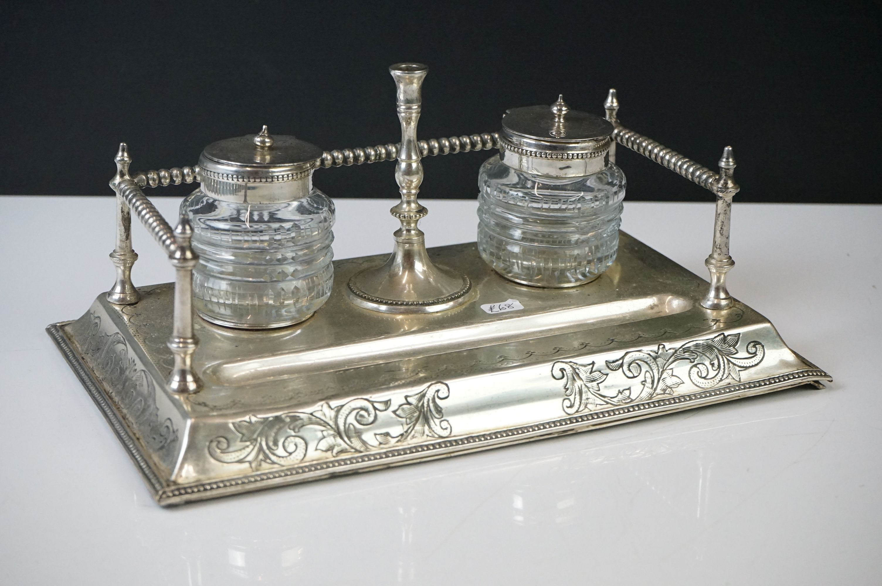 An antique silver plated standish with taper holder and double inkwells.