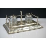 An antique silver plated standish with taper holder and double inkwells.