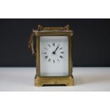 A brass cased carriage clock with beveled glass panels and white enamel dial, complete with key.