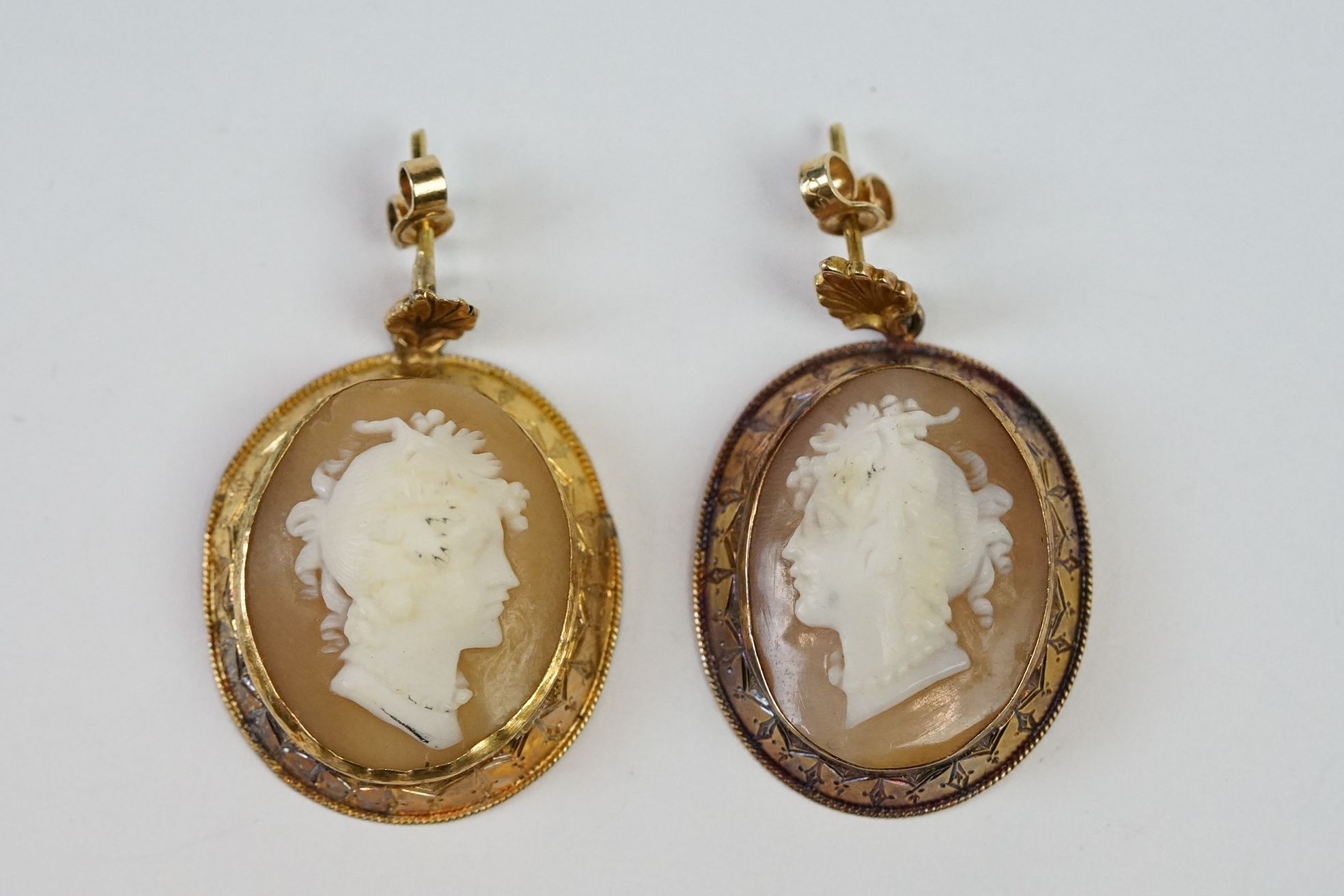 A pair of yellow metal cameo earrings.