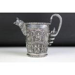 An Indian white metal jug with ornate decoration of Indian figures in tradition dress with