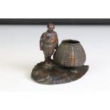 An oriental bronzed table top match striker in the form of a man with basket.