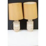Pair of cylindrical pottery table lamps, with incised bands of repeating geometric motifs on cream