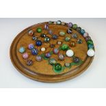 A turned wooden solitaire board together with associated marbles.