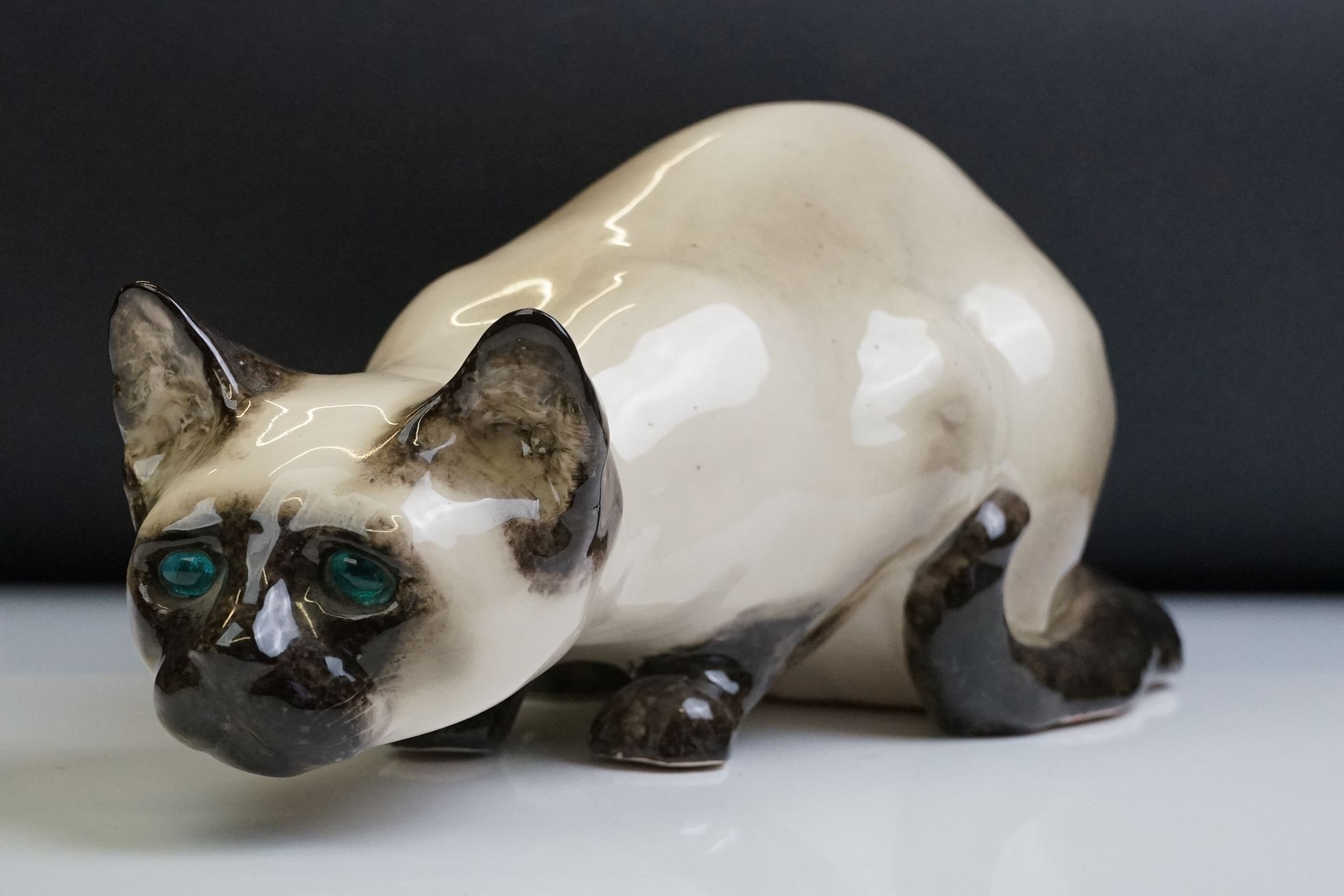 Winstanley pottery figure of a crouching Siamese cat with blue glass eyes, signed to the base and